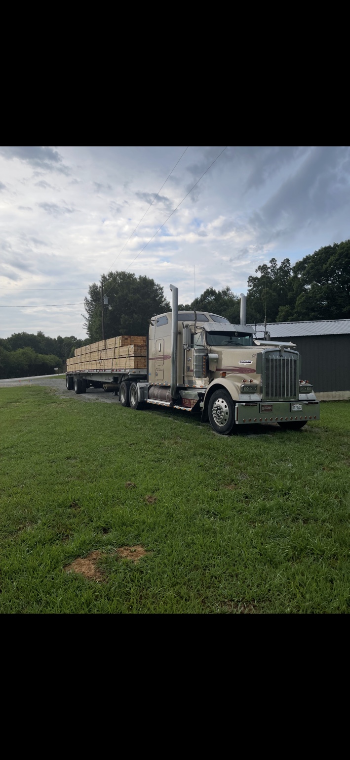White truck with lumber secured on a flatbed trailer