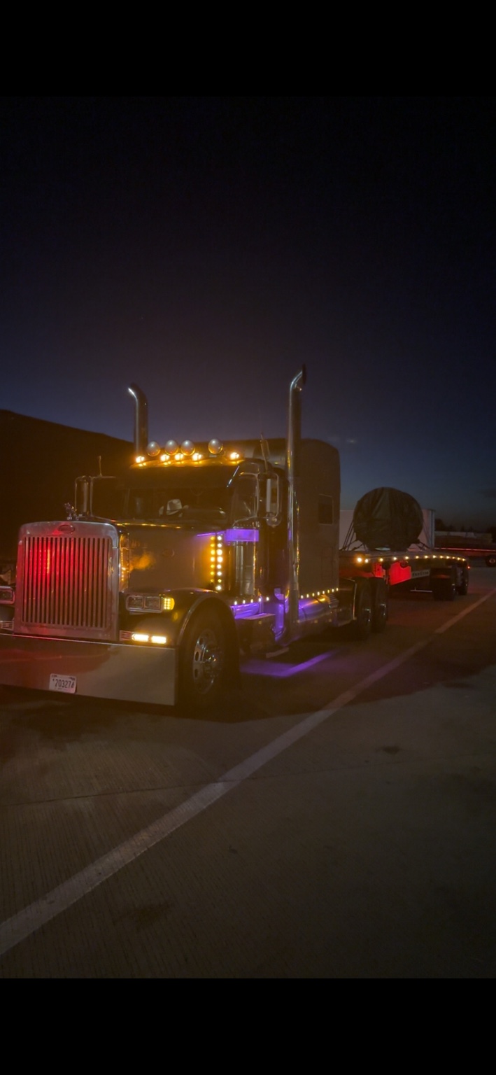 Dark truck with lights on at night carrying a covered load
